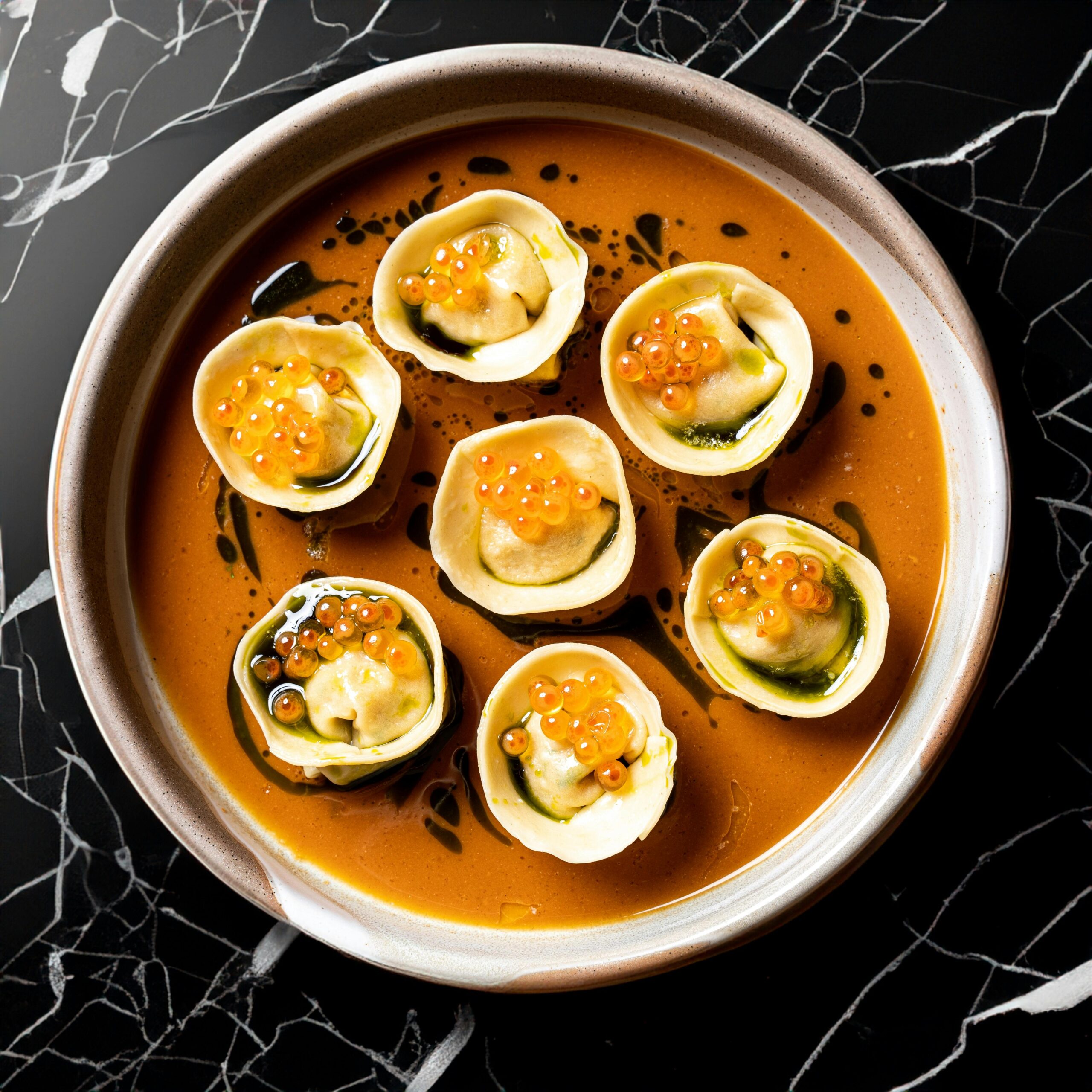 Elegant top-view of gourmet veggie dumplings in rich sauce, garnished with caviar for a luxurious meal.